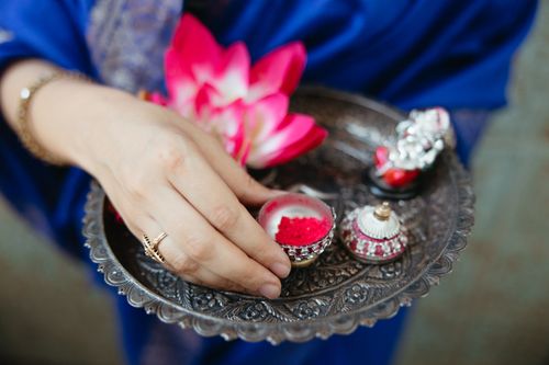 Free A close-up of a hand holding a traditional tray with sindoor, lotus, and ritual items. Stock Photo