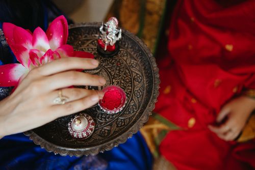 Free A hand holding a decorated tray with pink flowers and ritual items symbolizing cultural traditions. Stock Photo