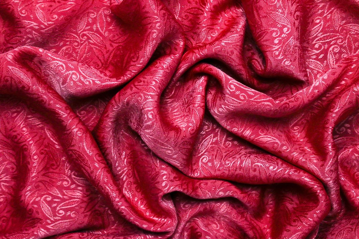 Tecido vermelho com padrão floral tom sobre tom, amarrotado e visto de perto