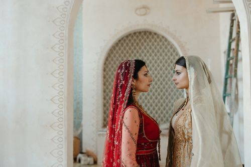 Free Two women in traditional South Asian attire face each other in an ornate setting, exuding cultural elegance. Stock Photo