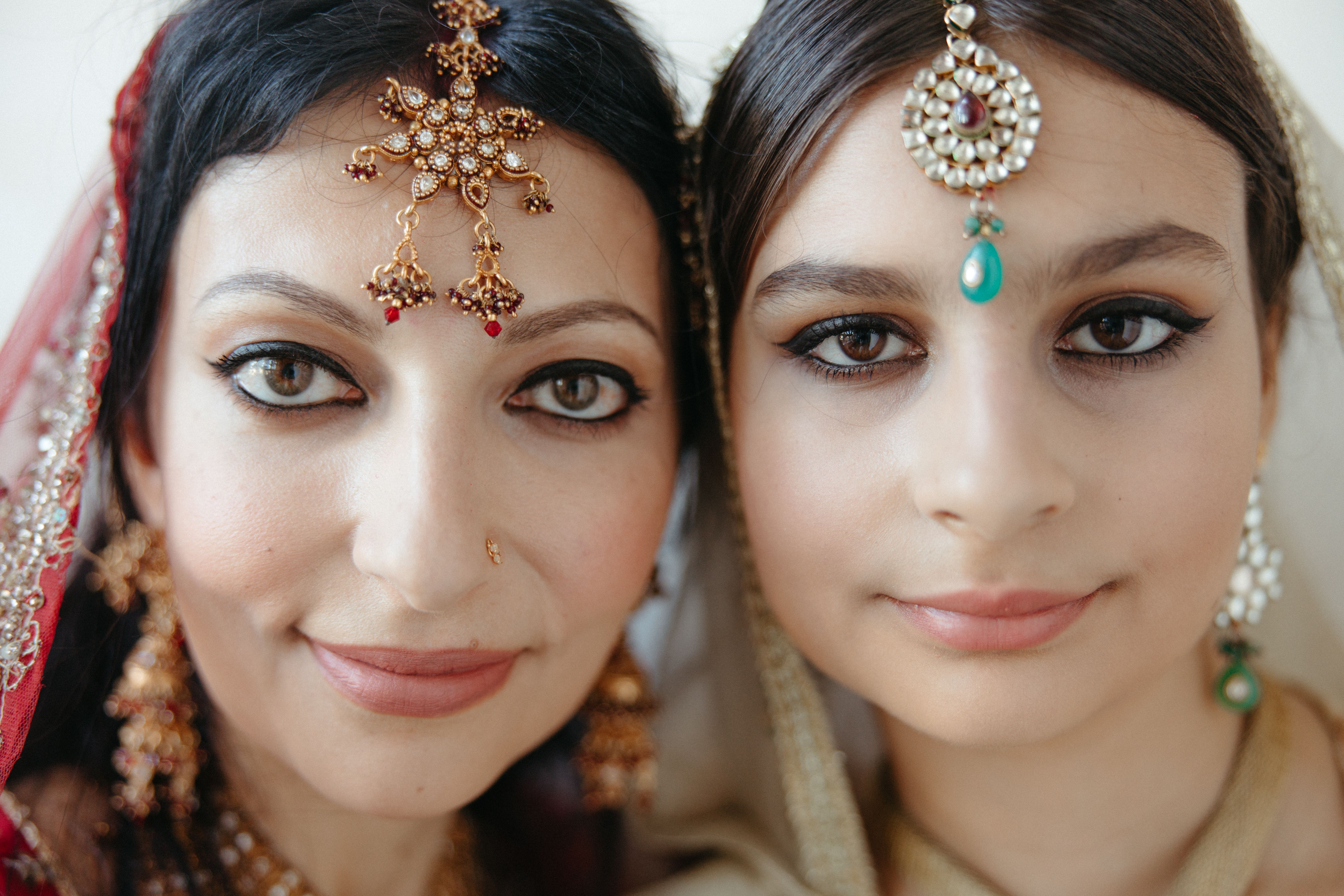 Close-up of mother and daughter in traditional South Asian attire with jewelry, showcasing cultural beauty.