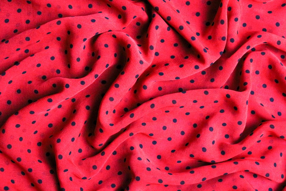 Close-up of red polka dot fabric with textured folds and vibrant colors. - Trends in Ladies' Dress Fabrics in Pakistan