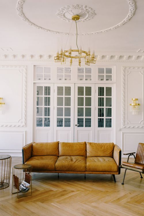 Free Luxurious interior design featuring a leather couch, chandelier, and white walls. Stock Photo