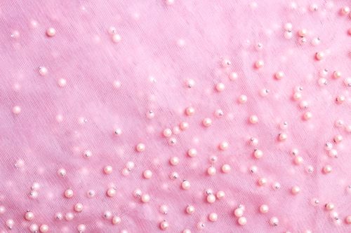 Free Close-up of pink fabric adorned with pearls and beads, showcasing texture and elegance. Stock Photo