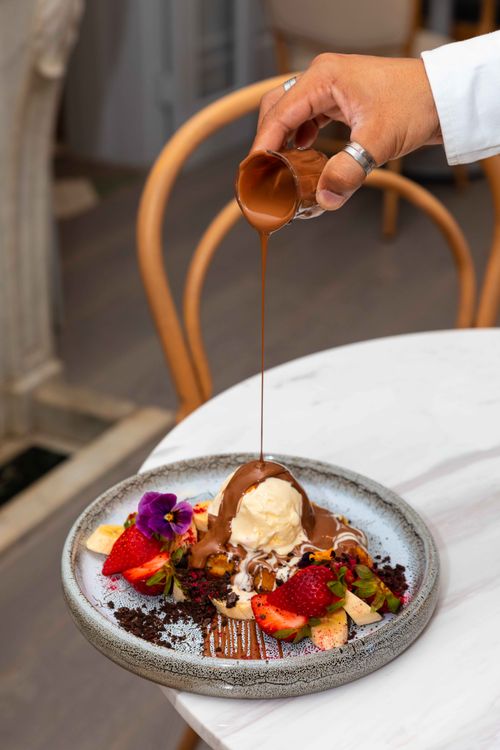 Free Delicious dessert with ice cream, strawberries, and chocolate drizzle on a white table. Stock Photo