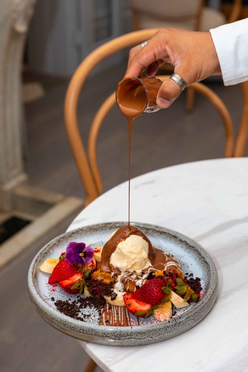 Free Delicious dessert with chocolate sauce, ice cream, and fresh fruits garnished beautifully. Stock Photo