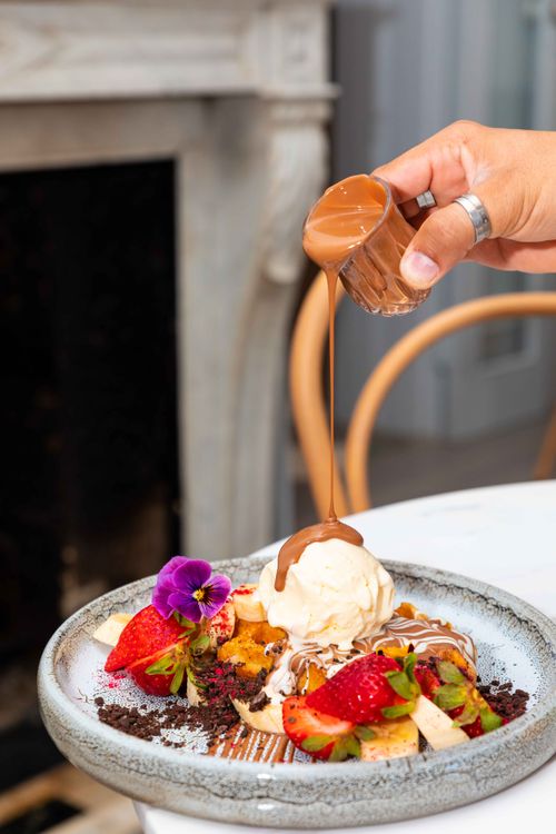 Free Decadent dessert with chocolate drizzle, strawberries, ice cream, and flower garnish on a plate. Stock Photo
