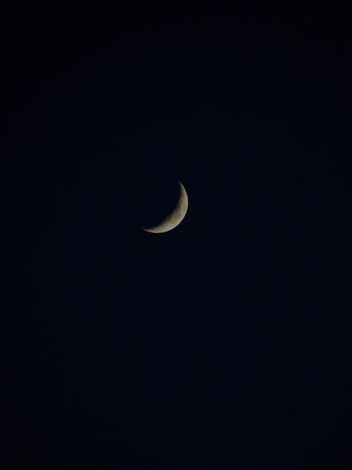 Crescent moon with spots glowing on dark sky at night high in universe