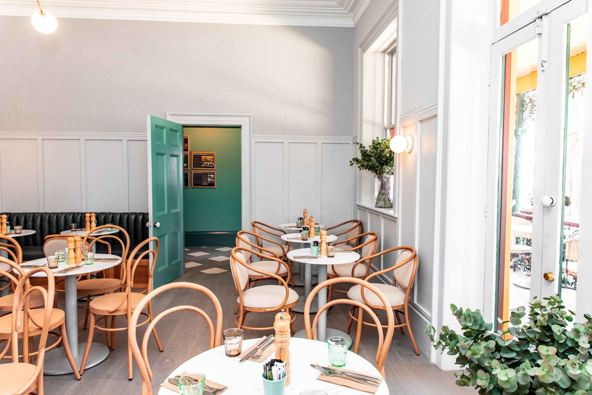 Bright and stylish restaurant interior with wooden chairs and white tables, ready for dining.