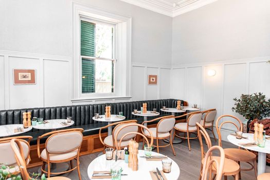 Bright modern restaurant interior featuring elegant round tables and chairs with natural lighting.