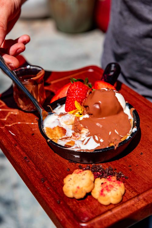 Free Close-up of a chocolate-covered dessert topped with strawberries on a wooden tray. Stock Photo