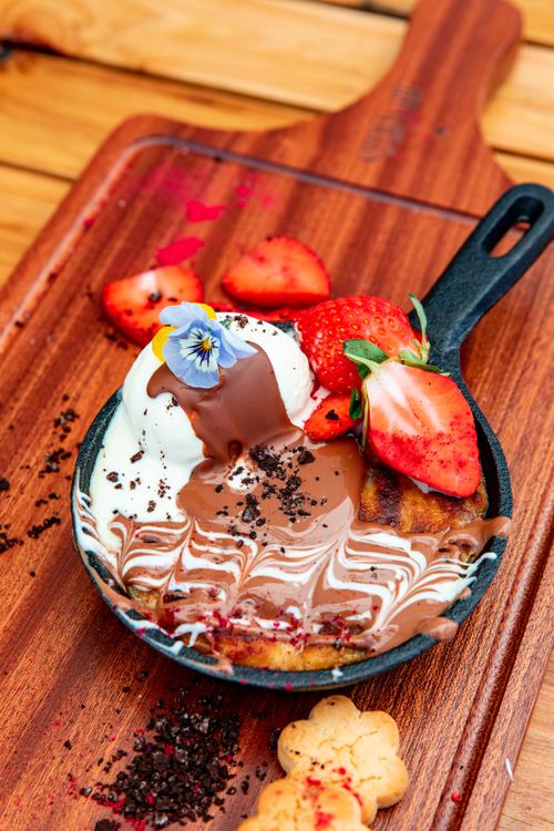 Free Close-up of a delicious dessert with strawberries, chocolate, and vanilla ice cream in a skillet. Stock Photo