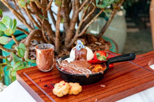 Free Delicious dessert with ice cream and chocolate drizzle in a skillet, garnished with strawberry and blue flower. Stock Photo