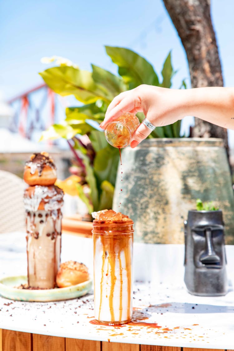 A Person Pouring Brown Sauce On White Cream