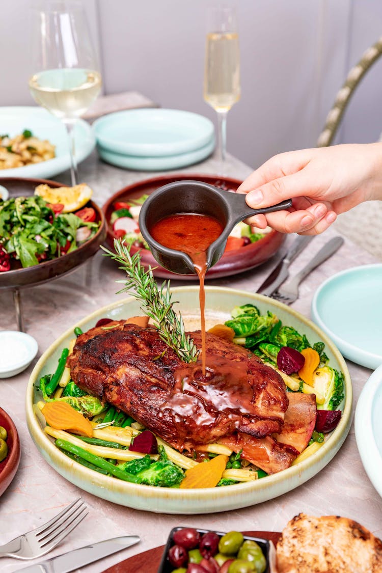 A Person Pouring Gravy On Cooked Meat