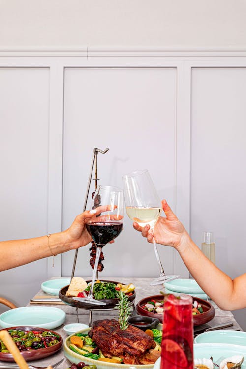 Free People Holding Clear Wine Glasses With Red and White Wine Stock Photo