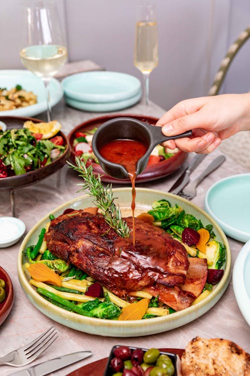 A Person Pouring Sauce over the Baked Meat