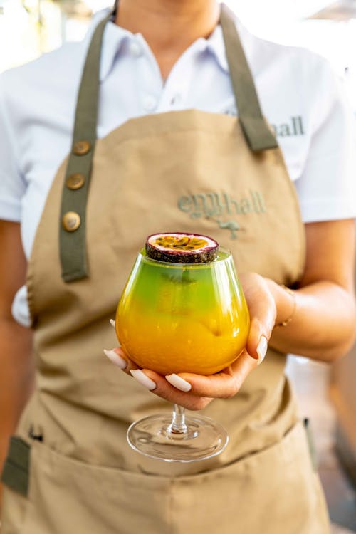 A Person Holding a Cocktail with Sliced Passion Fruit