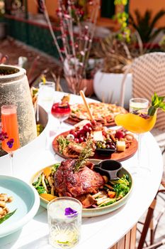 Exquisite outdoor dining setting with a variety of gourmet dishes and vibrant drinks on a sunny day.
