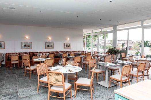 Elegant dining area with natural light, wooden chairs, and modern decor in a chic restaurant setting.