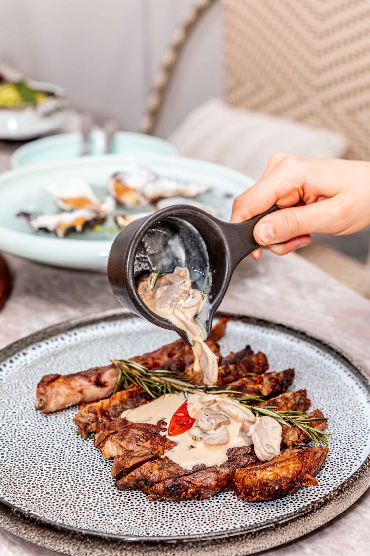 A Person Pouring Mushroom Gravy On Ribs