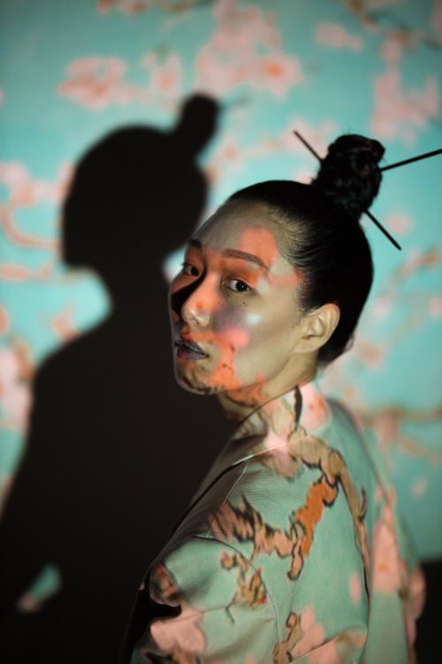 Free A creative portrait of a woman with floral projections, creating striking shadows. Stock Photo