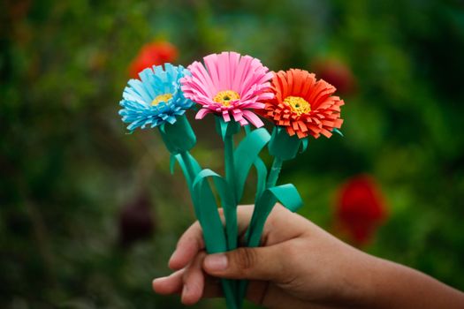 Vibrant paper flowers resembling gerberas held in hand, perfect for DIY decor.