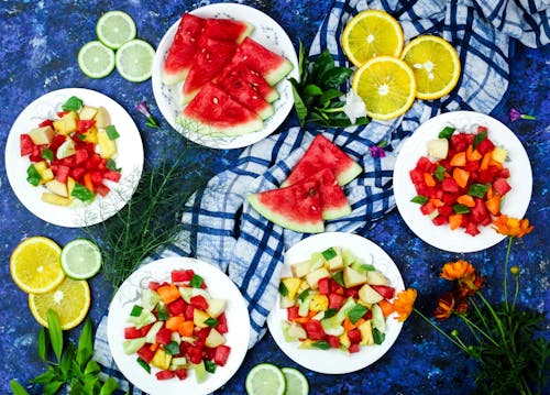Free Plates of Sliced Fruits on a Blue Surface Stock Photo
