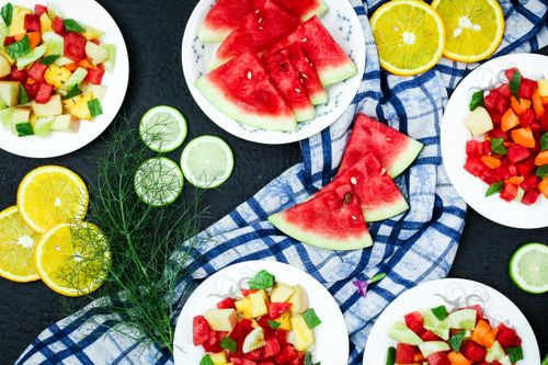 Free A colorful flat lay of fresh fruit slices on ceramic plates, perfect for summer refreshment. Stock Photo
