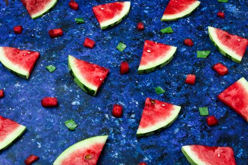 Free Bright and fresh triangular watermelon slices arranged on a vibrant blue textured background. Stock Photo