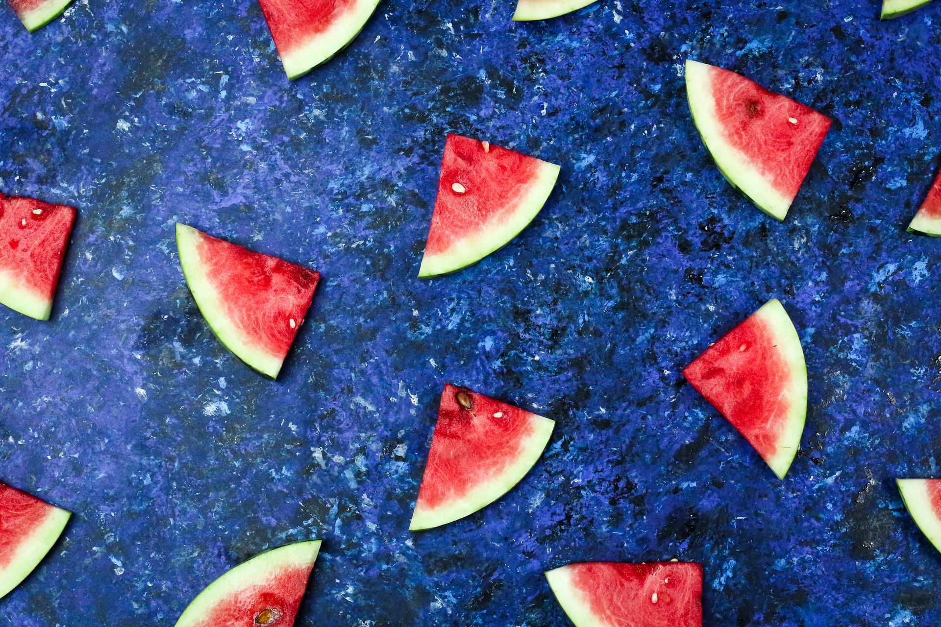 Triangular watermelon slices arranged on a vibrant blue background, showcasing freshness and vibrant colors.
