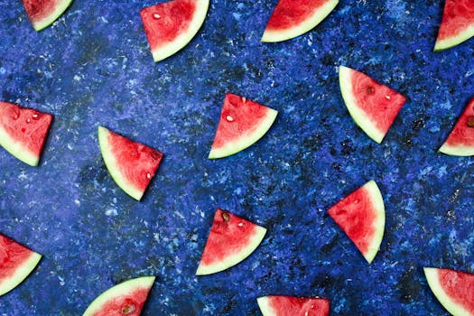 Flatlay of juicy watermelon slices on a vibrant blue textured surface.