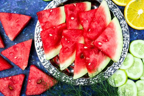 Free Freshly sliced watermelon, cucumbers, and oranges on a silver plate for a healthy snack. Stock Photo