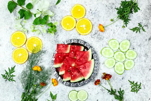 Vibrant top view of watermelon, oranges, cucumbers, and flowers for healthy eating.
