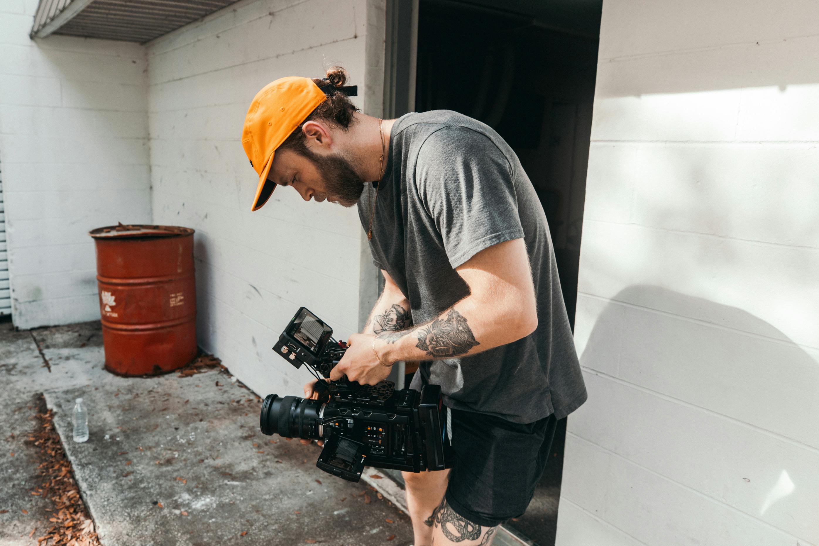 man in grey crew neck t shirt and yellow hat holding black dslr camera