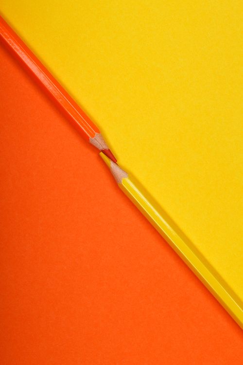Free Orange and yellow pencils on matching colored background in diagonal arrangement. Stock Photo