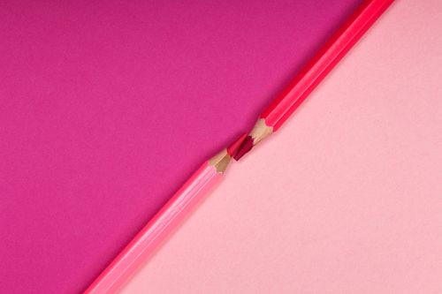 Free Two broken red color pencils against a vibrant pink background, symbolizing creativity and contrast. Stock Photo