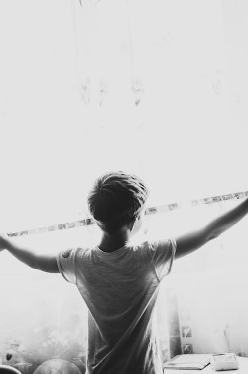 Grayscale Photo of Boy Extending His Arm 