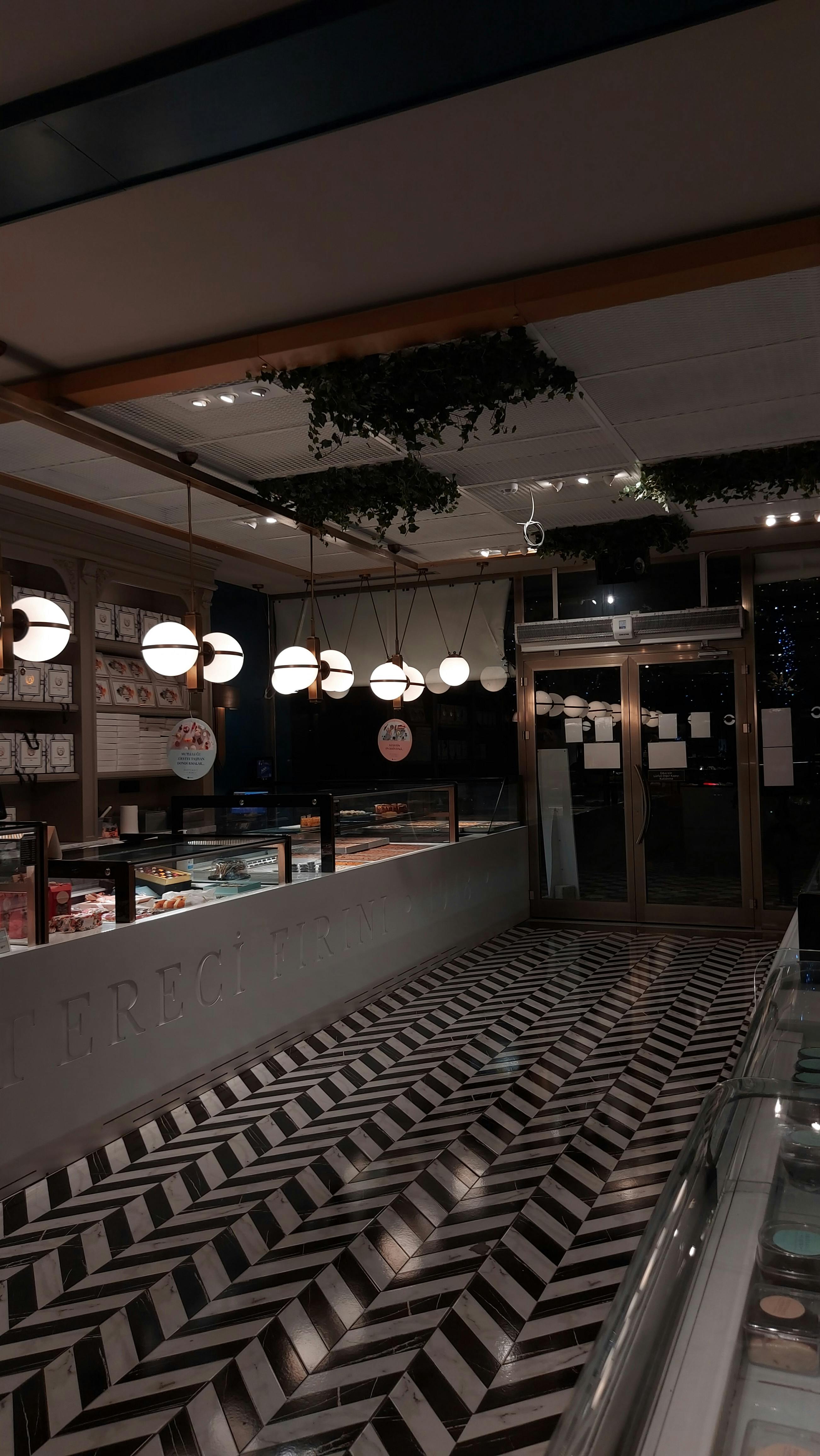 Elegant café interior with modern lighting and geometric flooring, offering a cozy ambiance.