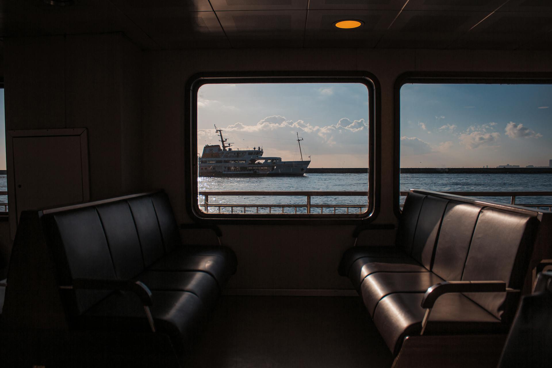 Interior ferry view with ship seen through window at sunset on open sea.