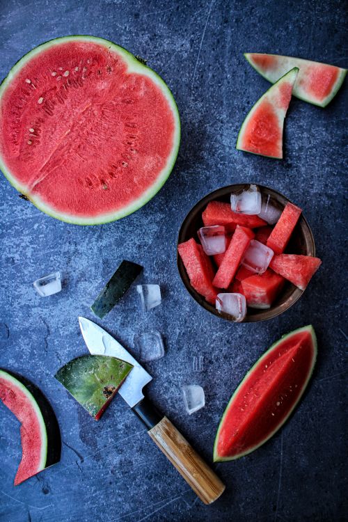 Free High-angle shot of fresh watermelon slices on dark surface with knife and ice cubes. Stock Photo