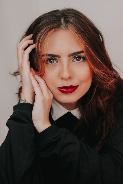 Free Close-up portrait of a young woman with striking red lips, posing indoors with confident expression. Stock Photo