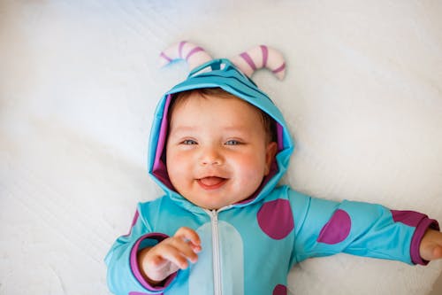 Free Smiling Baby in Pajamas Lying in Bed Stock Photo