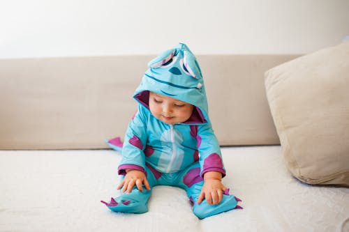 Baby Wearing a Blue Costume Sitting on a Sofa