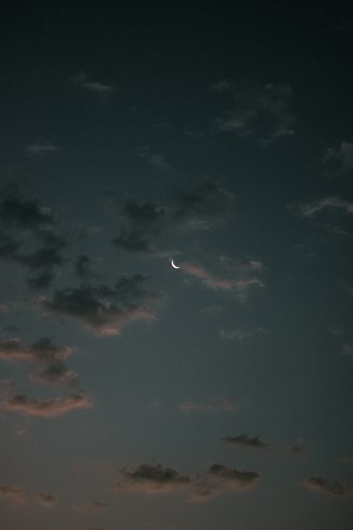 Free A peaceful evening sky featuring a dreamy crescent moon surrounded by gentle clouds. Stock Photo