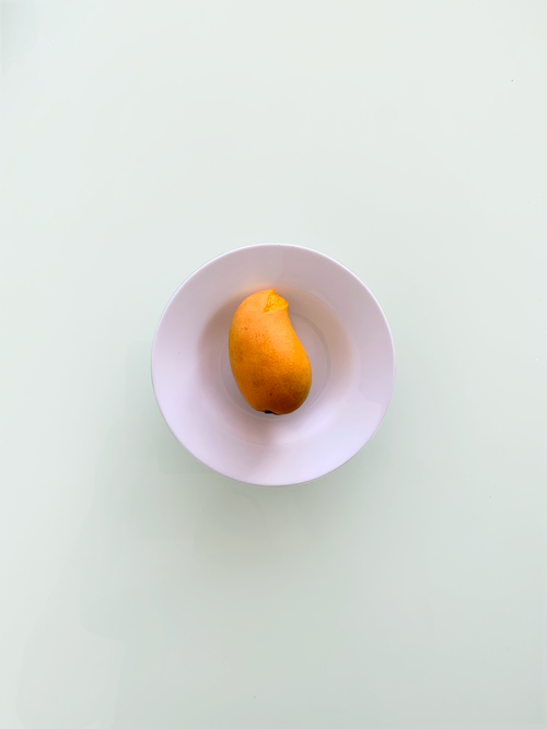 Free Ripe mango in a white bowl shot from above with a minimalist style. Stock Photo