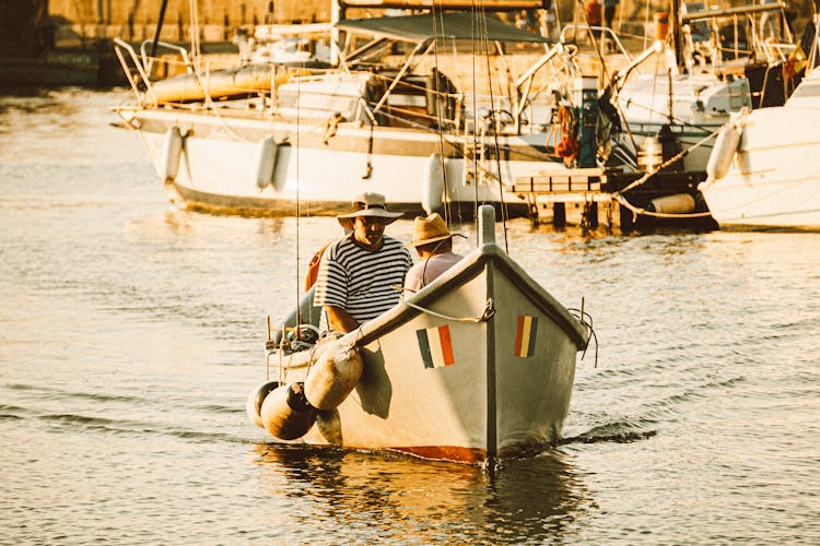 Men In Sailboat In Water On Sunset