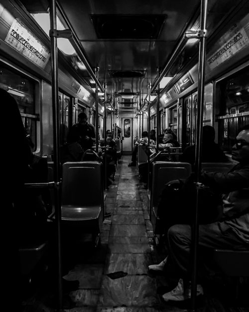Free Monochrome view of a subway train interior with commuters seated during transit. Stock Photo