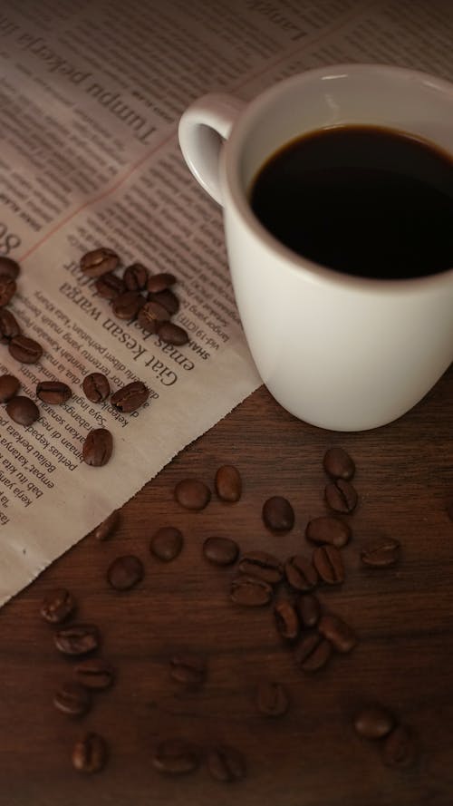 Cup of Coffee and Coffee Beans on Wooden Surface 