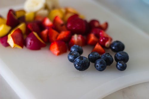 Berry Hitam Dengan Irisan Buah Di Piring Putih
